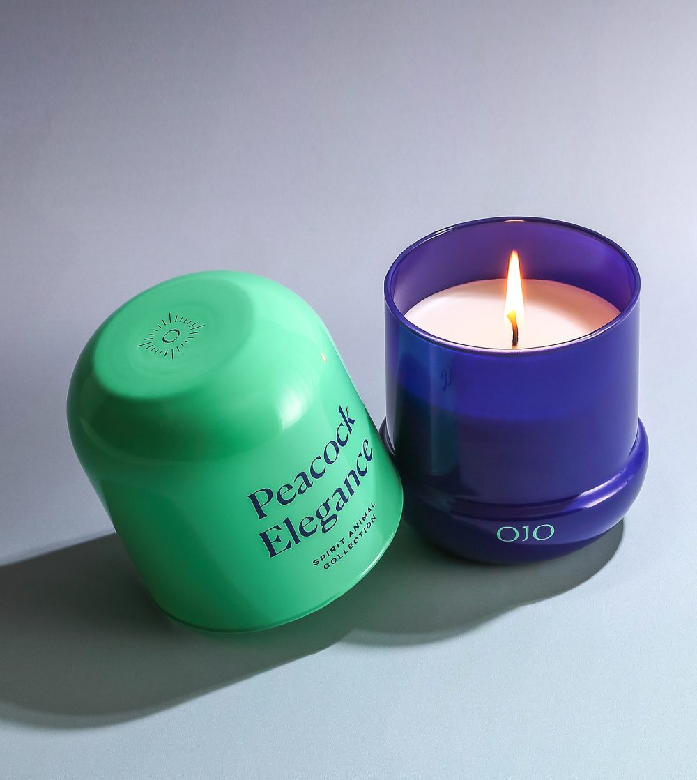 OJO Peacock Elegance candle collection with turquoise and blue glass jar, and white background