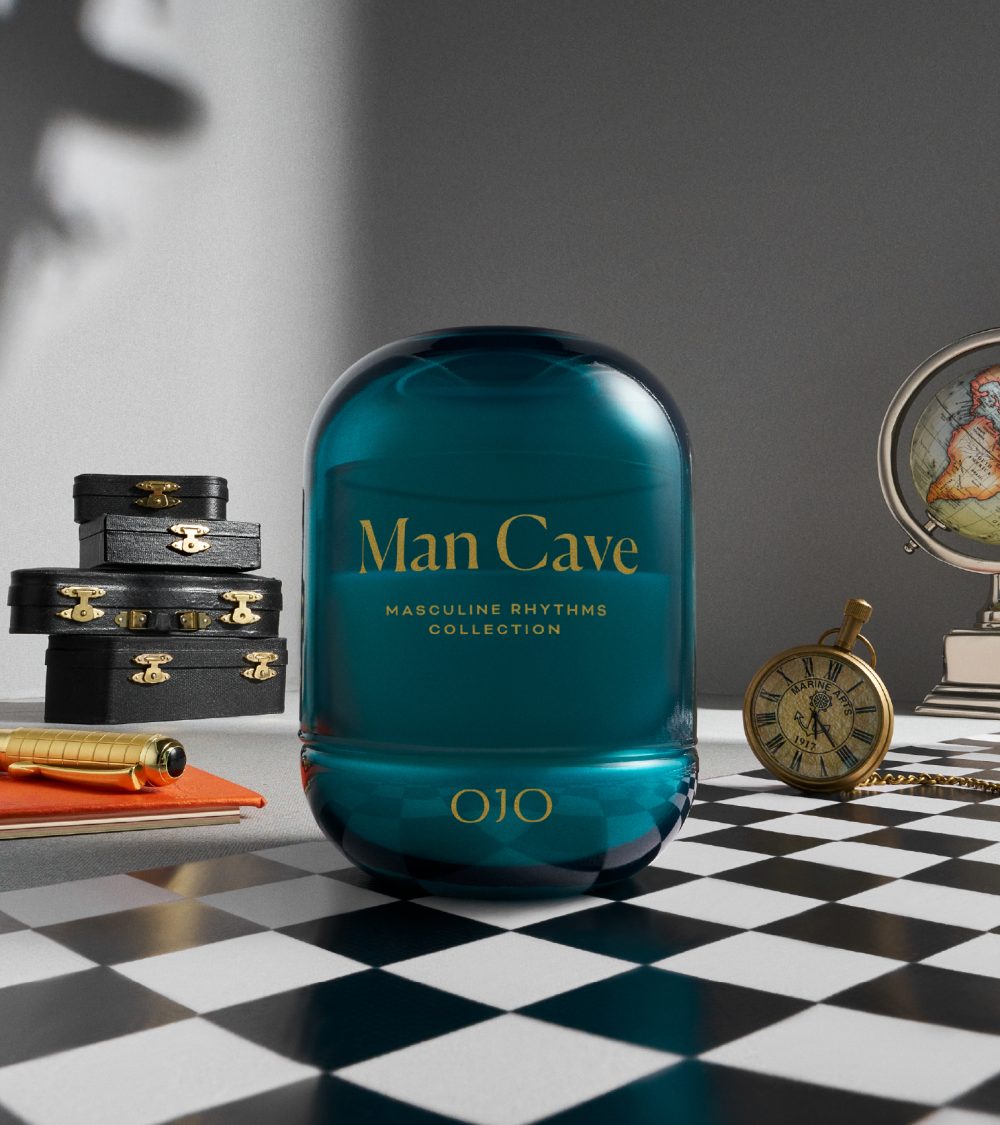 OJO Man Cave candle collection with blue glass jar, golden printed typography and checkered background