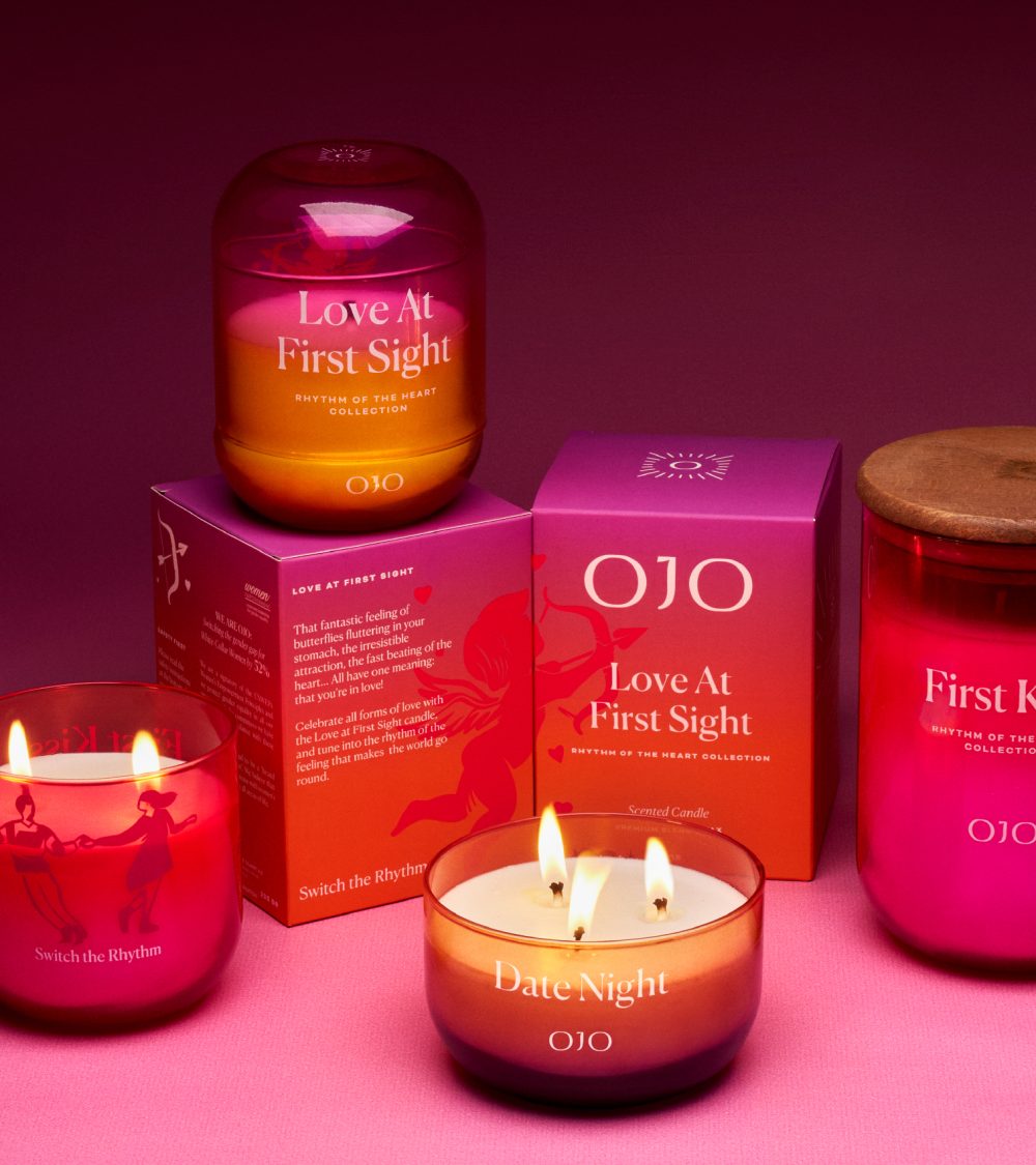 OJO Rhythm of the Heart candle collection with gradient colored glass jars, gradient colored packaging boxes and pink background