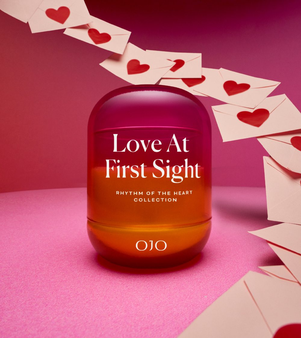 OJO Love at First Sight candle collection with gradient colored glass jars, flying envelopes with hearts and pink background