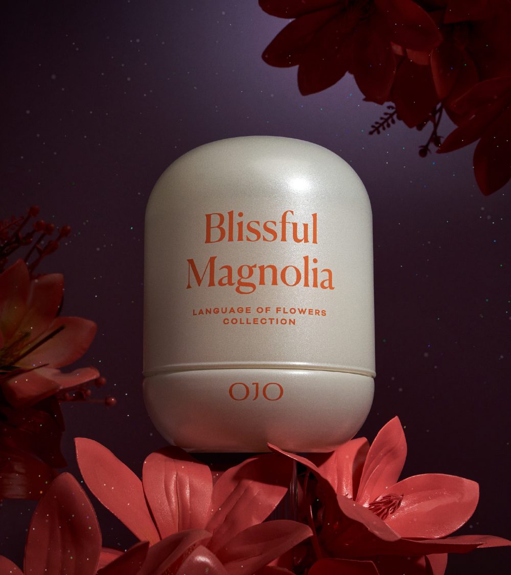 OJO Blissful Magnolia candle with white glass jar and dark background with pink magnolias
