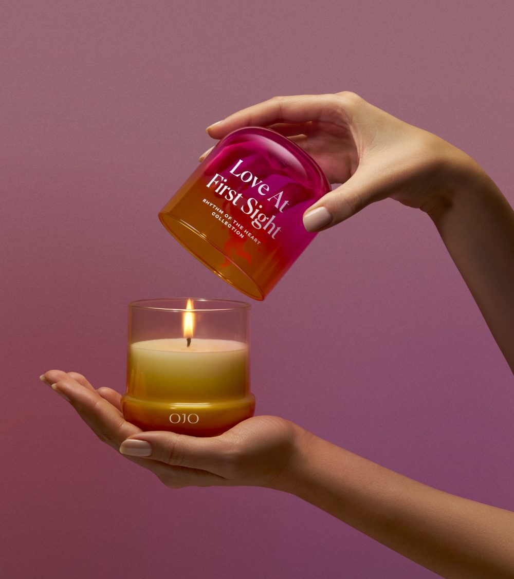 OJO Love at First Sight candle collection with gradient colored glass jar holding hands and pink background